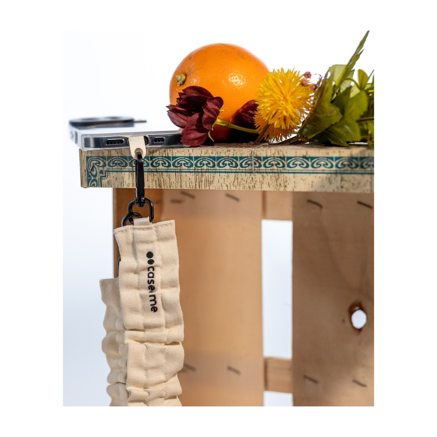 Un teléfono con cordón, naranja y flores sobre una tabla decorada.