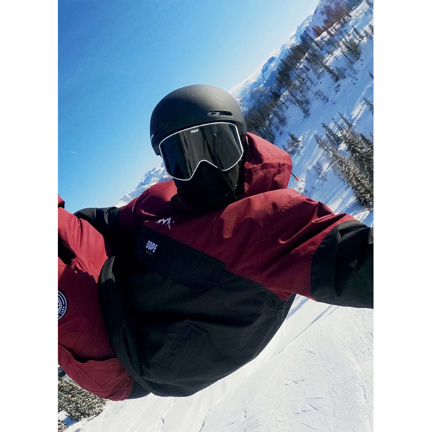 Snowboarder in roter Jacke und Helm springt vor verschneiten Bergen.