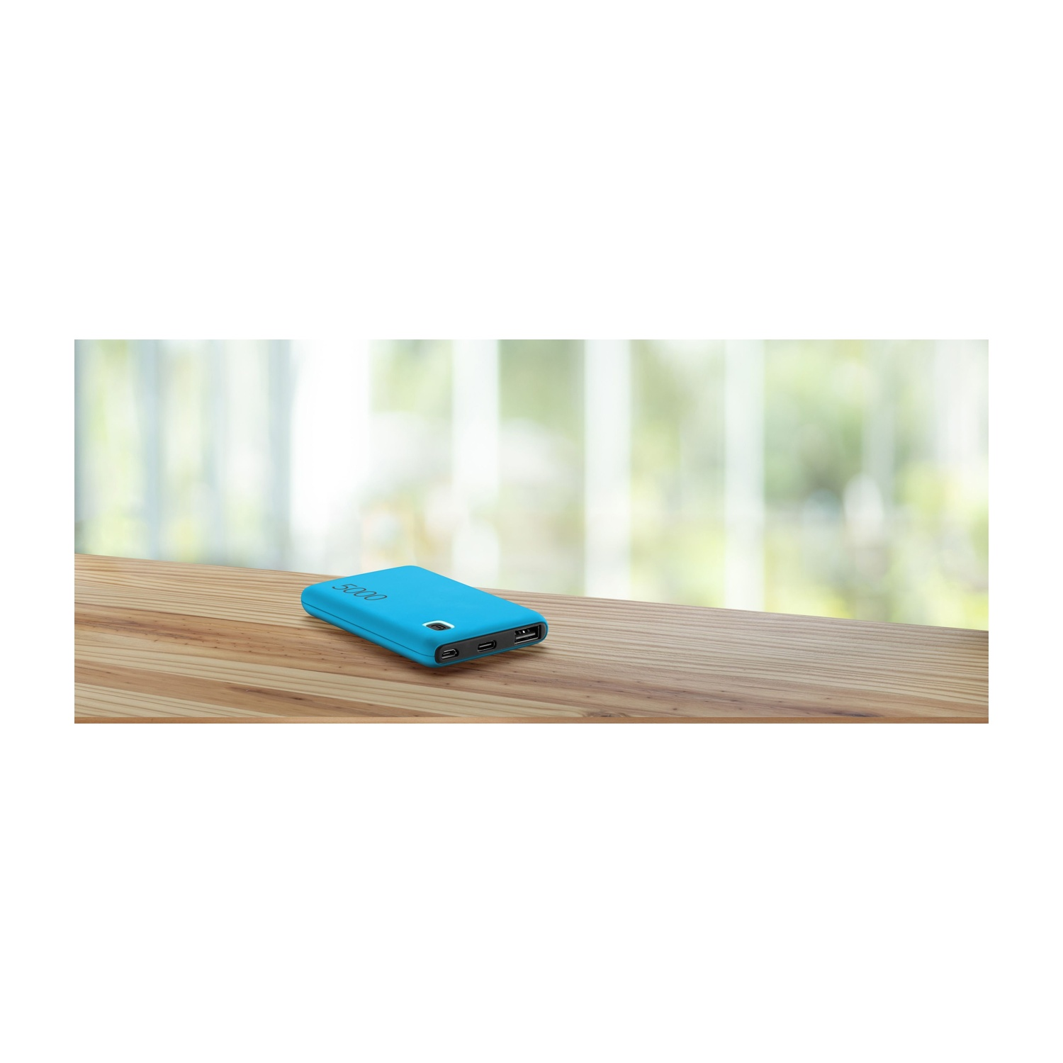 Un power bank blu da 5000mAh poggia su un tavolo di legno. Sfondo sfocato.