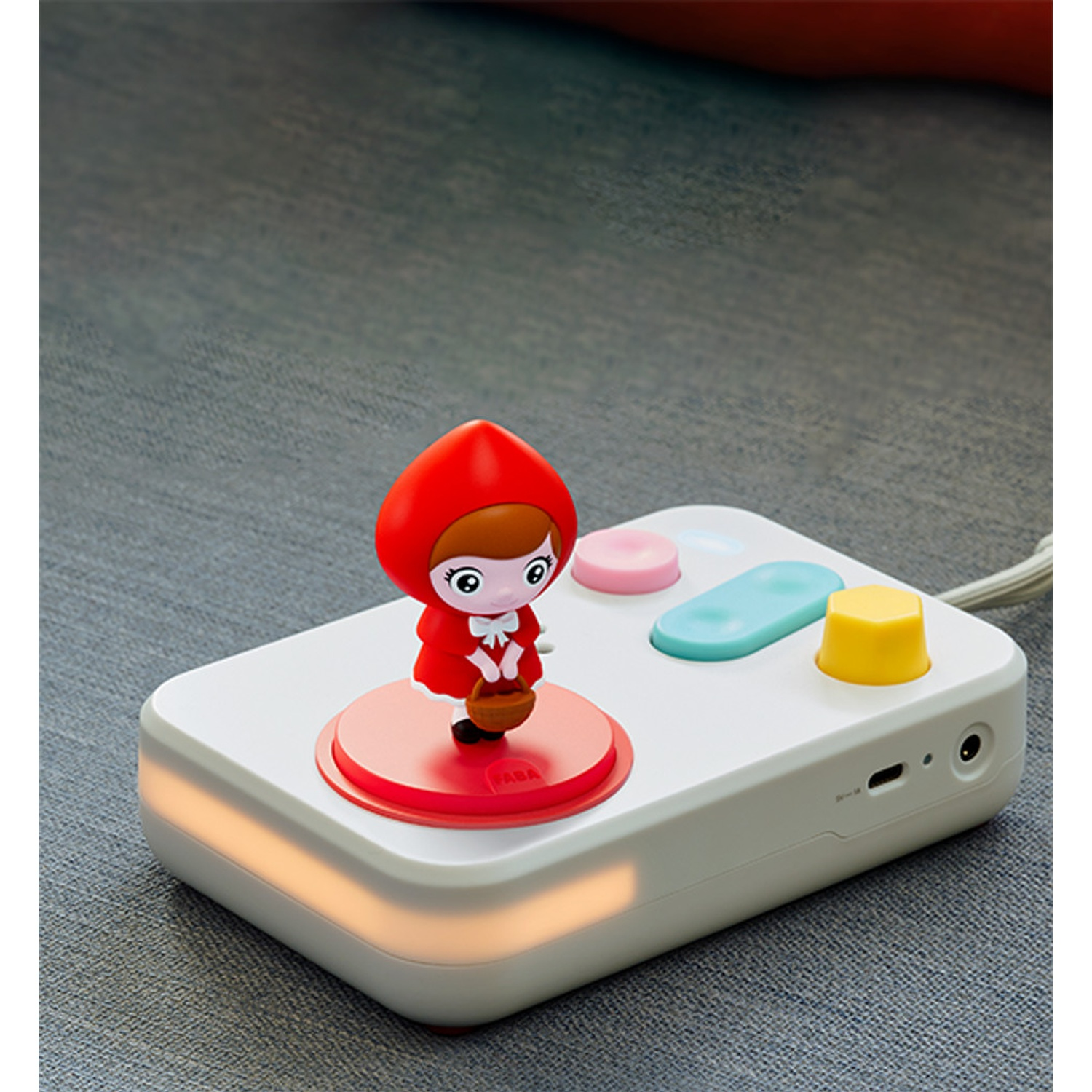 Una piccola figura con cappuccio rosso si trova su un dispositivo bianco con luci e pulsanti.