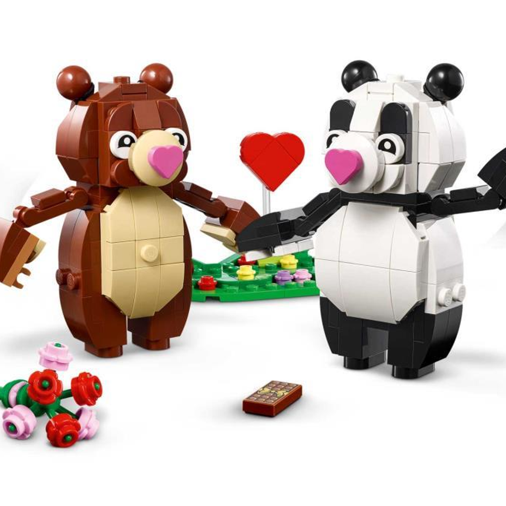 Kırmızı bir kalbin önünde el ele tutuşan Lego ayı ve Lego panda.
