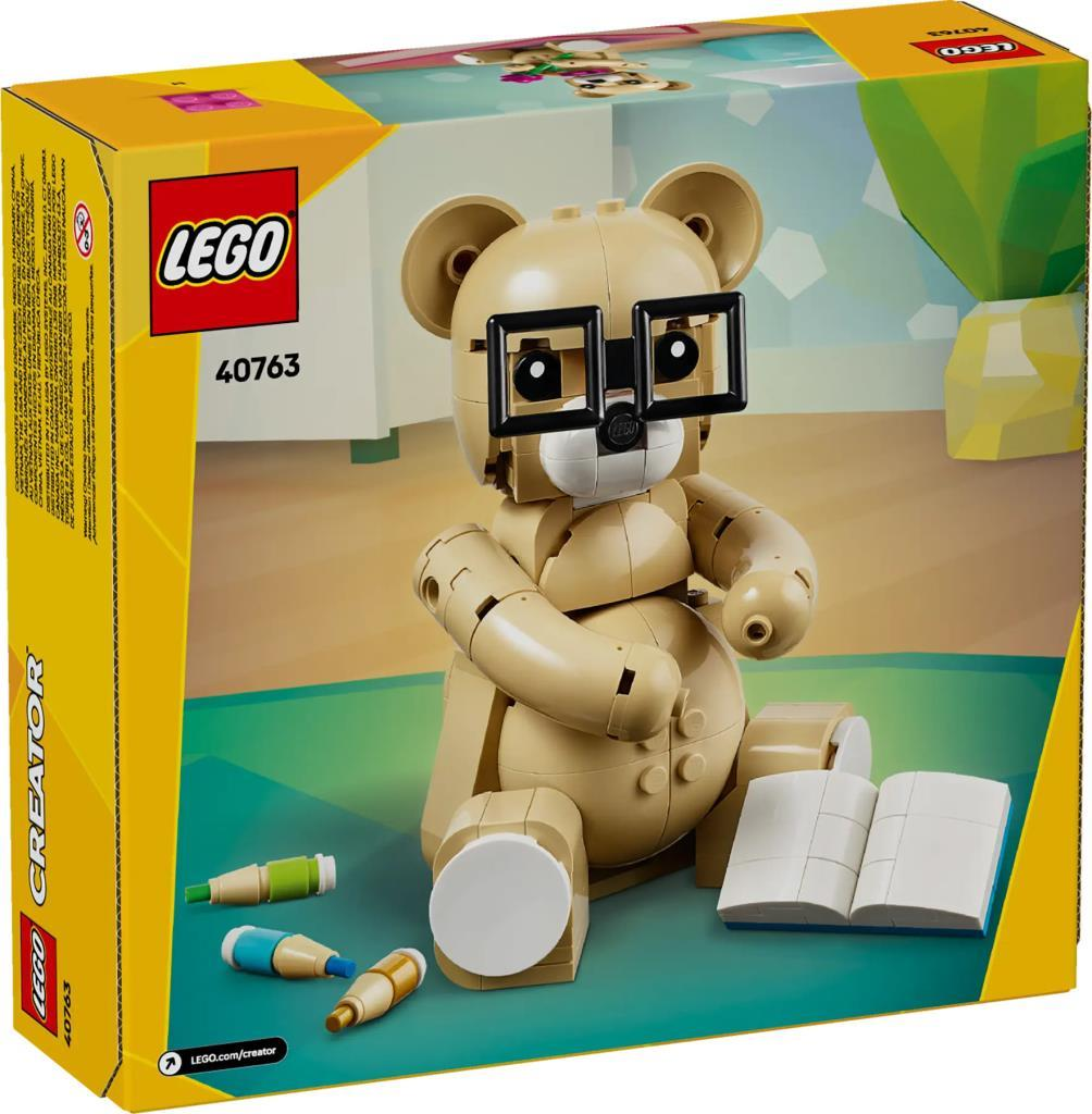 Un orsacchiotto Lego con occhiali siede vicino a matite e un libro.