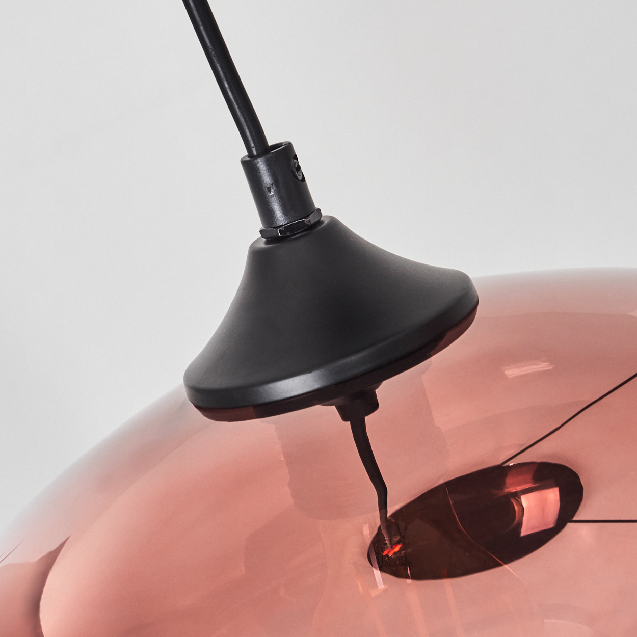 Nahaufnahme einer kupferfarbenen Lampe mit schwarzer Aufhängung.
