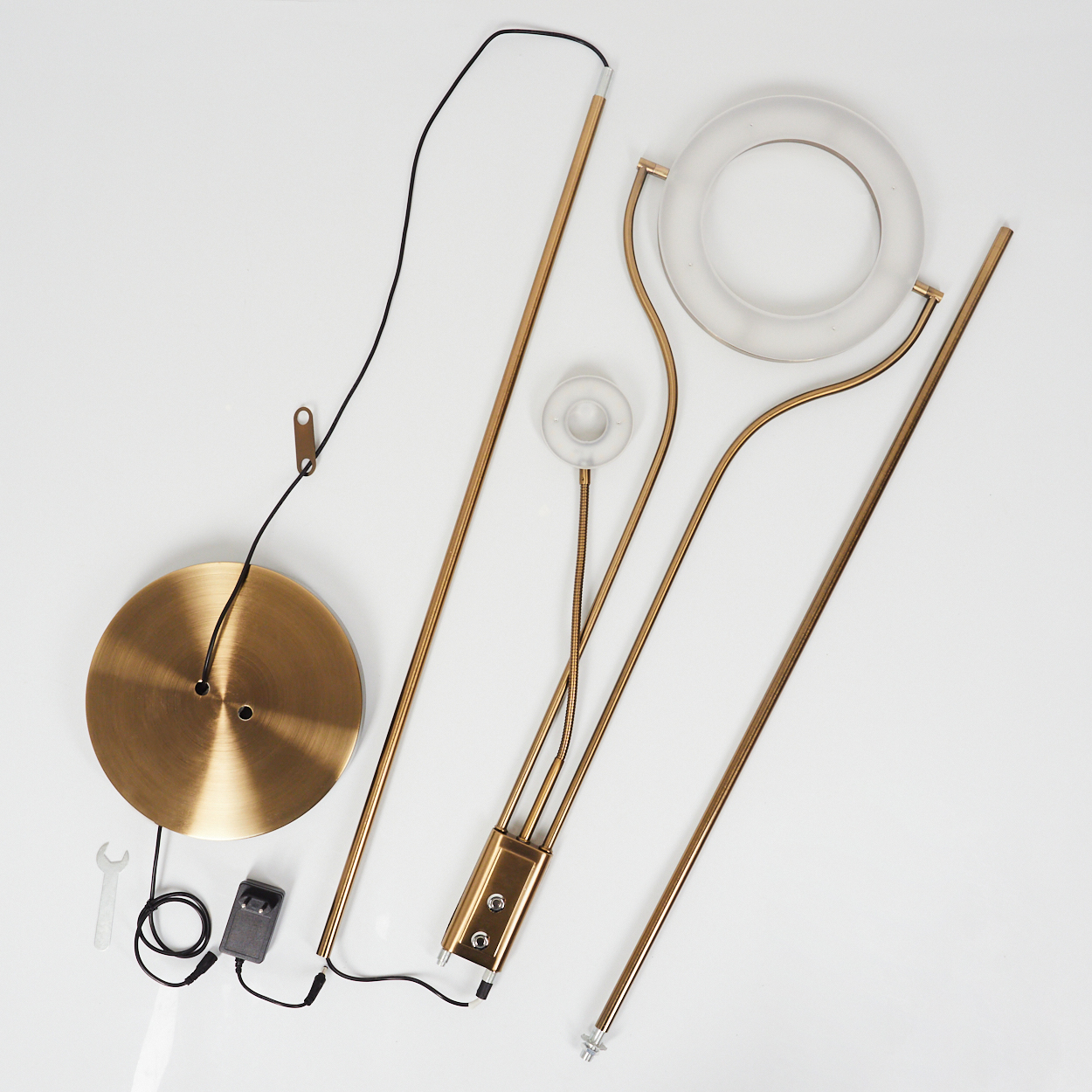 Teile einer Stehleuchte: Messingbasis, Stangen, Ringdiffusor, Netzteil.