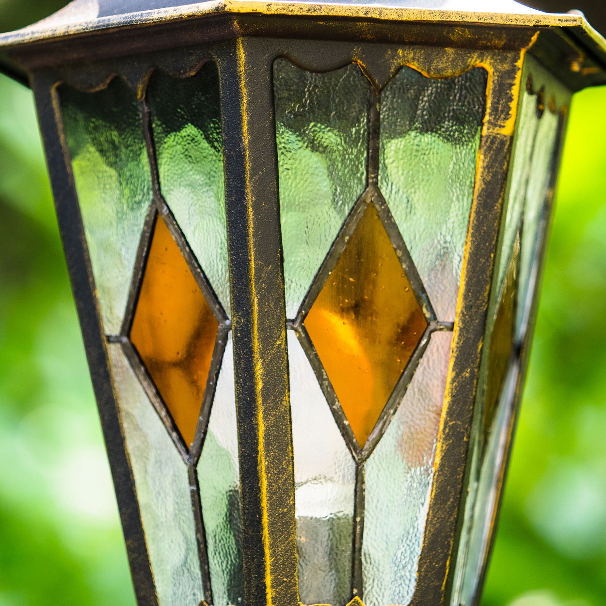 Ein Laternenkopf mit Glasfenstern in Rautenform und goldfarbenen Akzenten.