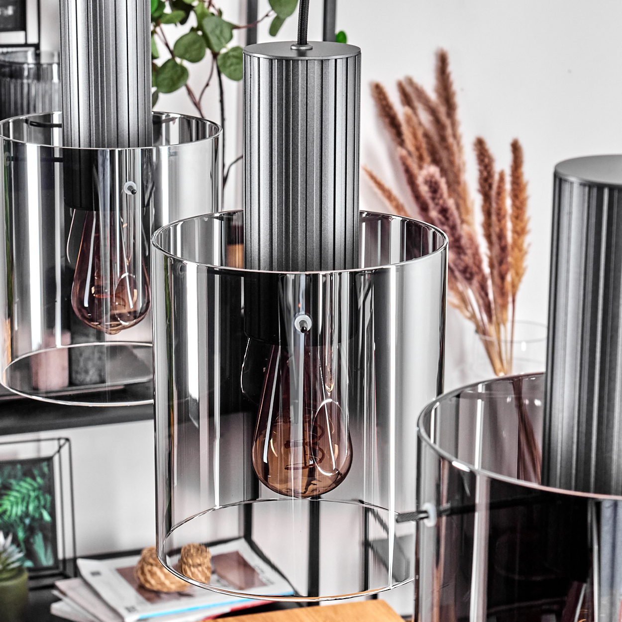 Moderne Hängeleuchte mit silbernem Zylinder und Glaszylinder, brauner Glühbirne.