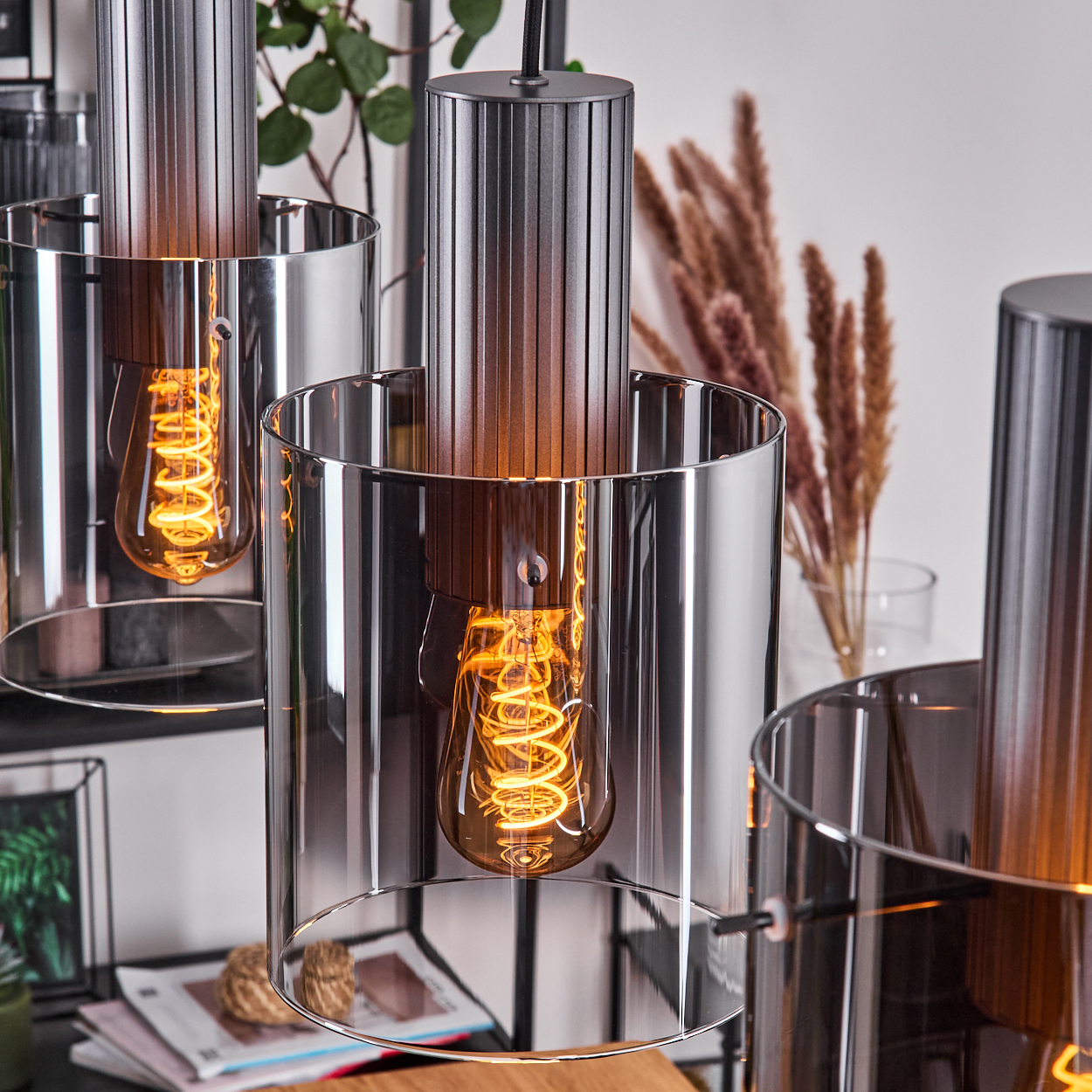 Nahaufnahme moderner Pendelleuchten mit freiliegenden Edison-Glühbirnen und gerippten Metallschirmen.