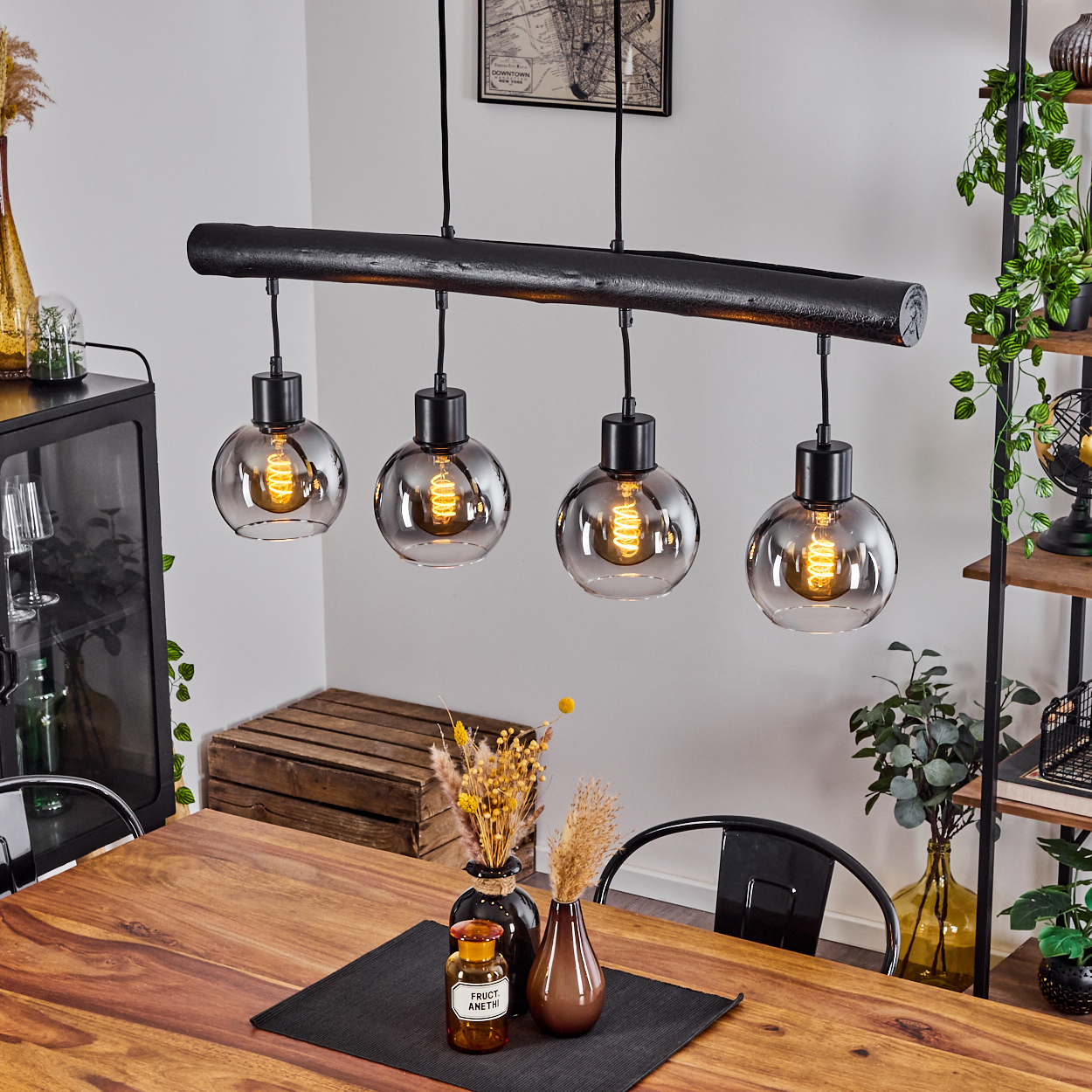 Ein moderner Kronleuchter mit vier Rauchglas-Kugellampen über einem Holztisch.