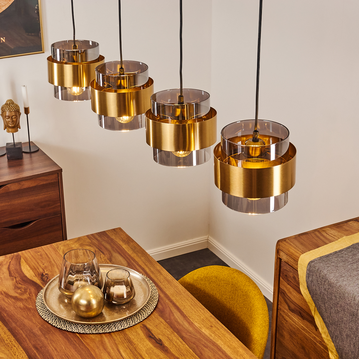 Vier Pendelleuchten mit Gold und Rauchglas über einem Holztisch.