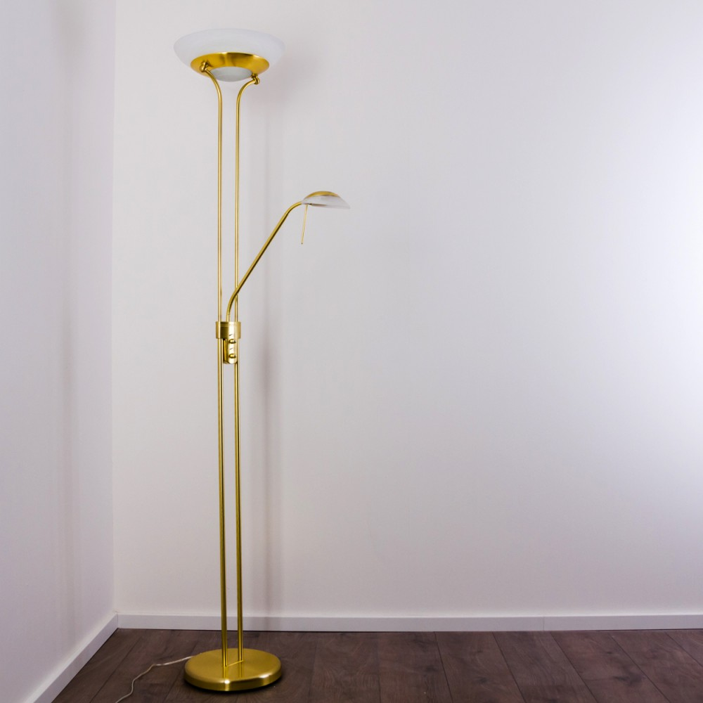 Ein goldener Stehleuchte mit zwei Lichtern steht in einer Ecke.