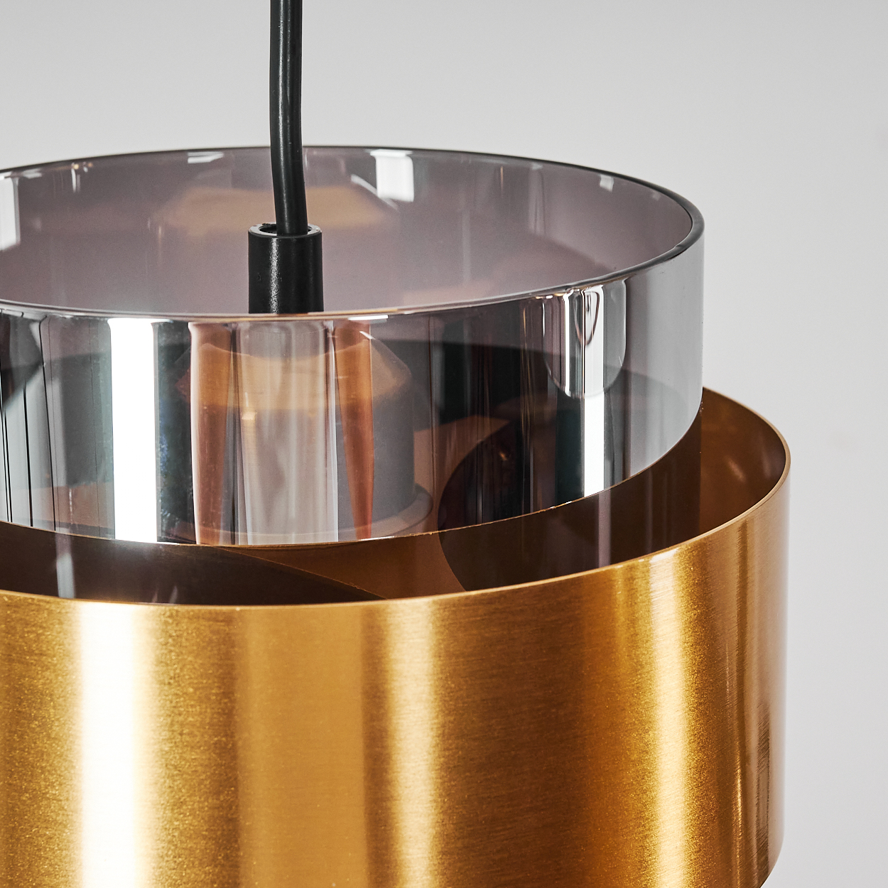Ein moderner Hängelampenschirm aus goldfarbenem Metall und Rauchglas.
