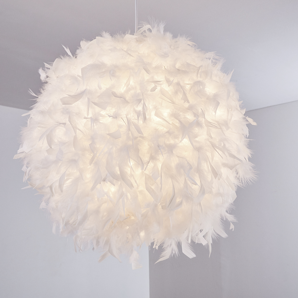 Eine kugelförmige, weiße Lampe aus Federn hängt von der Decke.
