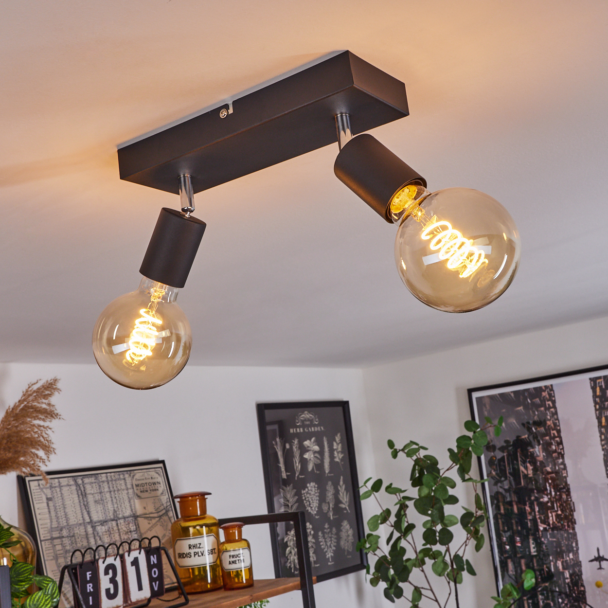 Eine schwarze Deckenlampe mit zwei Edison-Glühbirnen leuchtet hell.