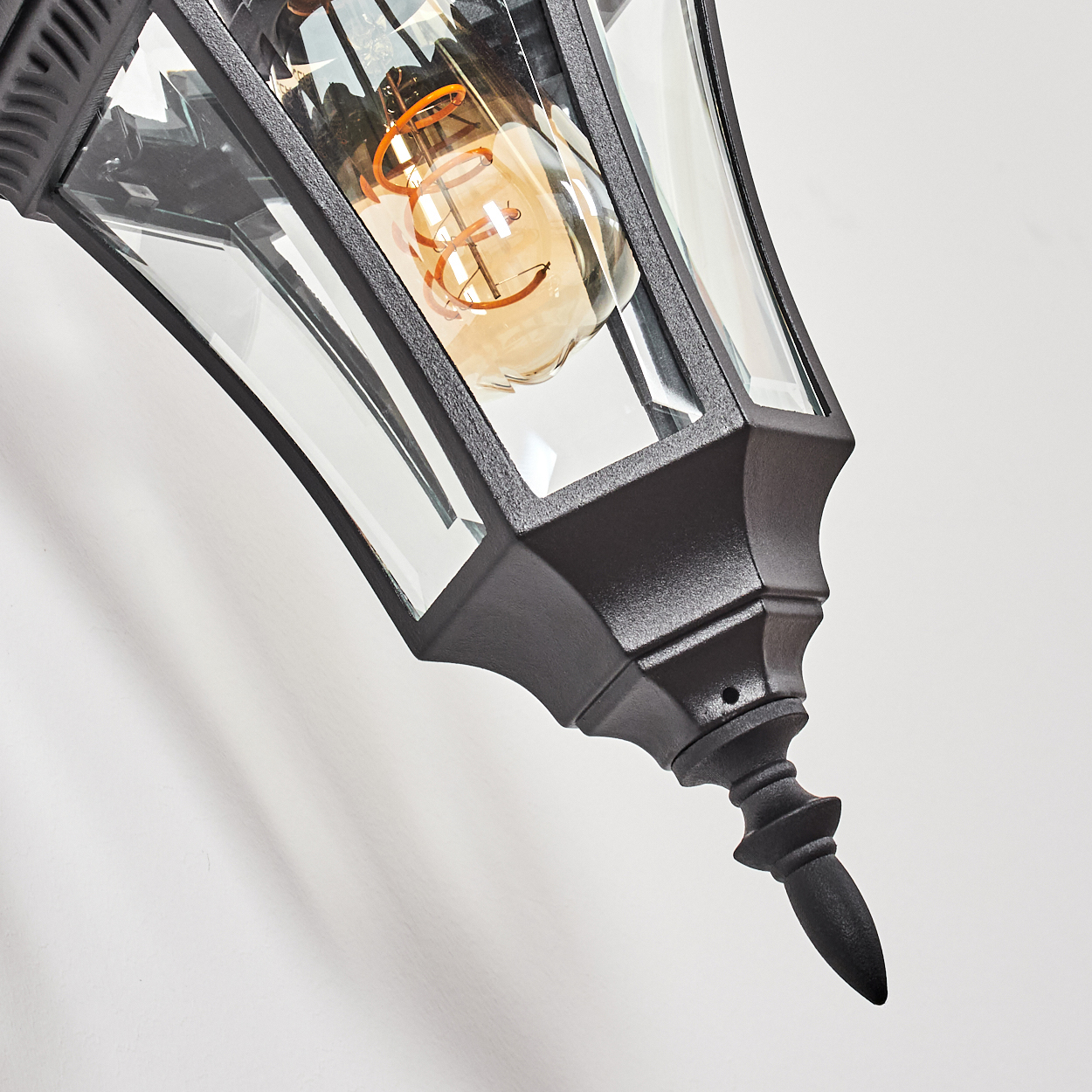 Eine schwarze Laterne mit Glaspaneelen und einer sichtbaren Glühbirne.