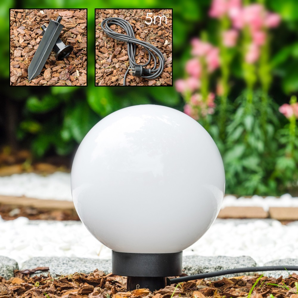 Eine weiße kugelförmige Lampe mit schwarzem Sockel steht im Garten.
