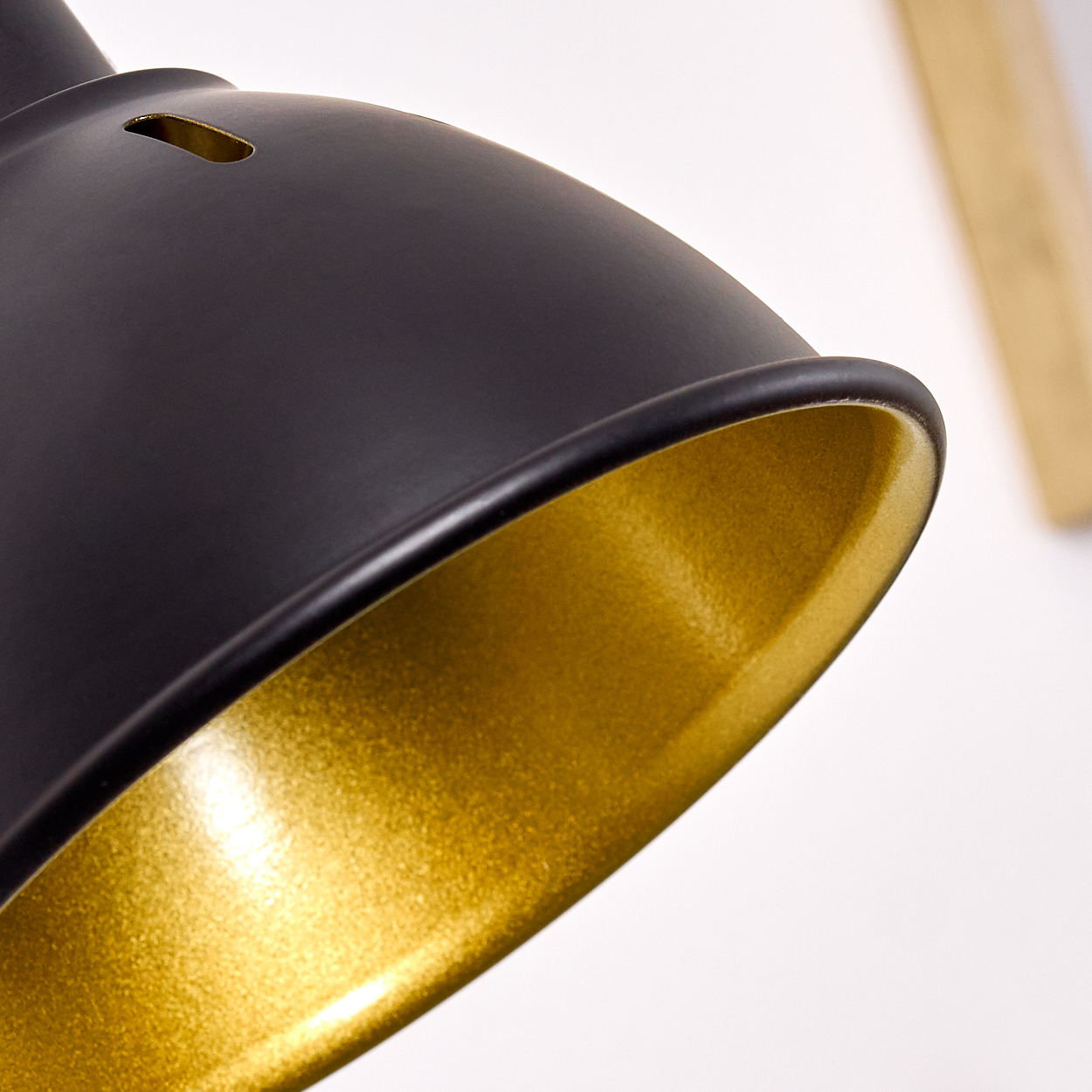 Ein schwarzer Lampenschirm mit goldener Innenseite, Nahaufnahme.