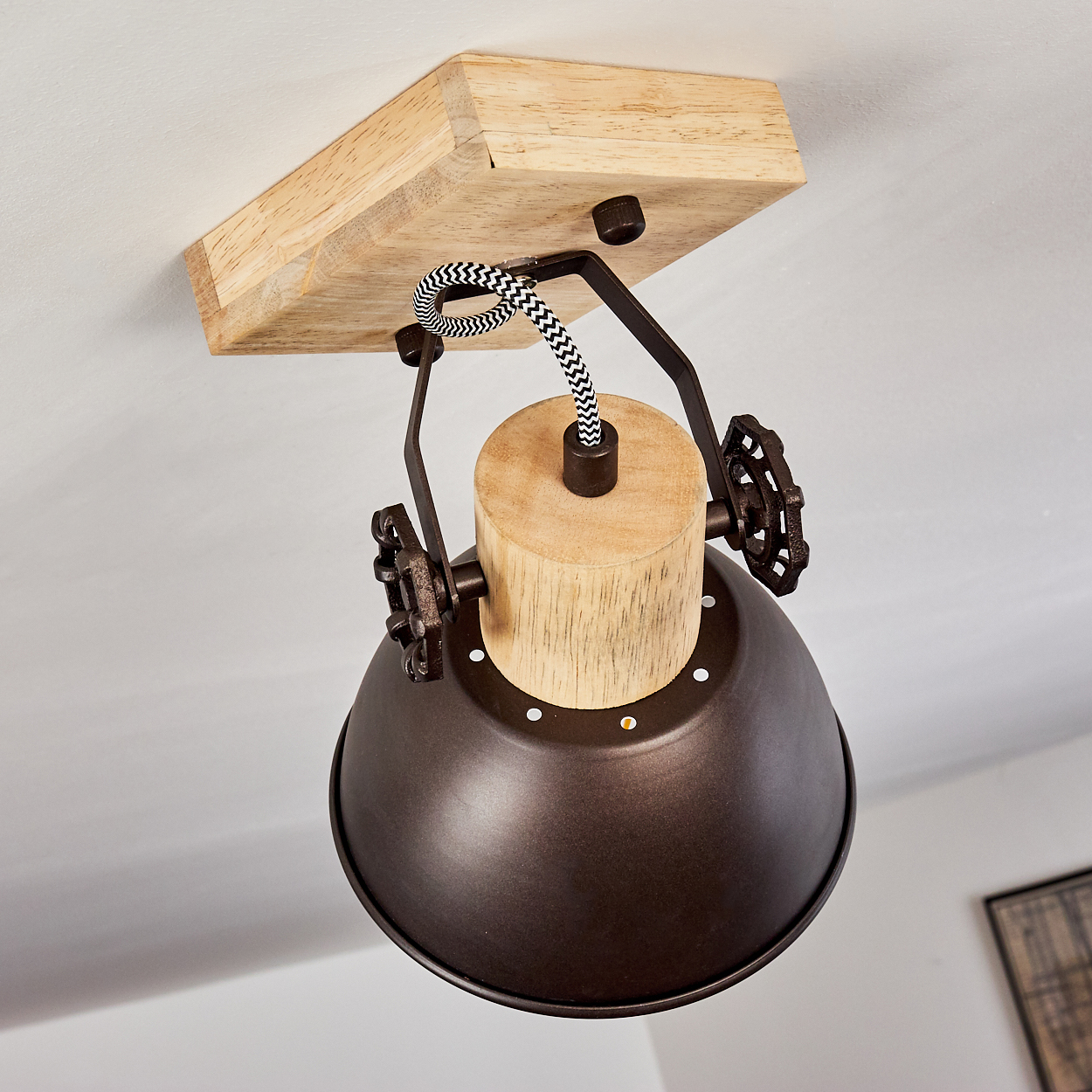 Eine Pendelleuchte mit Holzsockel, Metallschirm und Zierrädern.