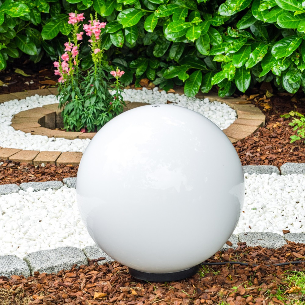 Große weiße Kugel Lampe im Garten mit Blumen und Kies.