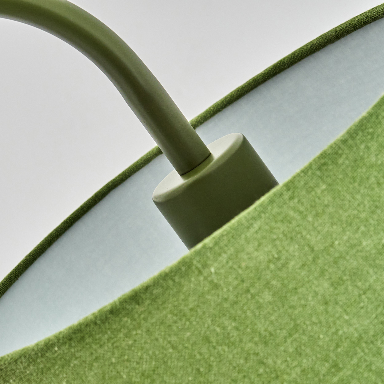 Nahaufnahme einer grünen Lampe mit gebogenem Arm und hellblauem Innenfutter.