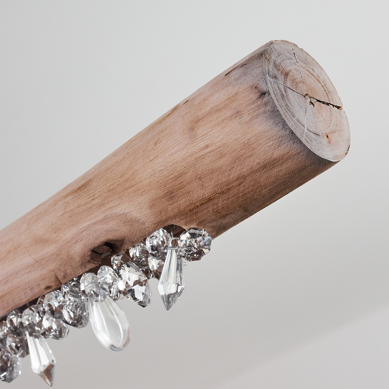 Ein grober Holzstamm mit funkelnden, facettierten Kristallen, die daran hängen.