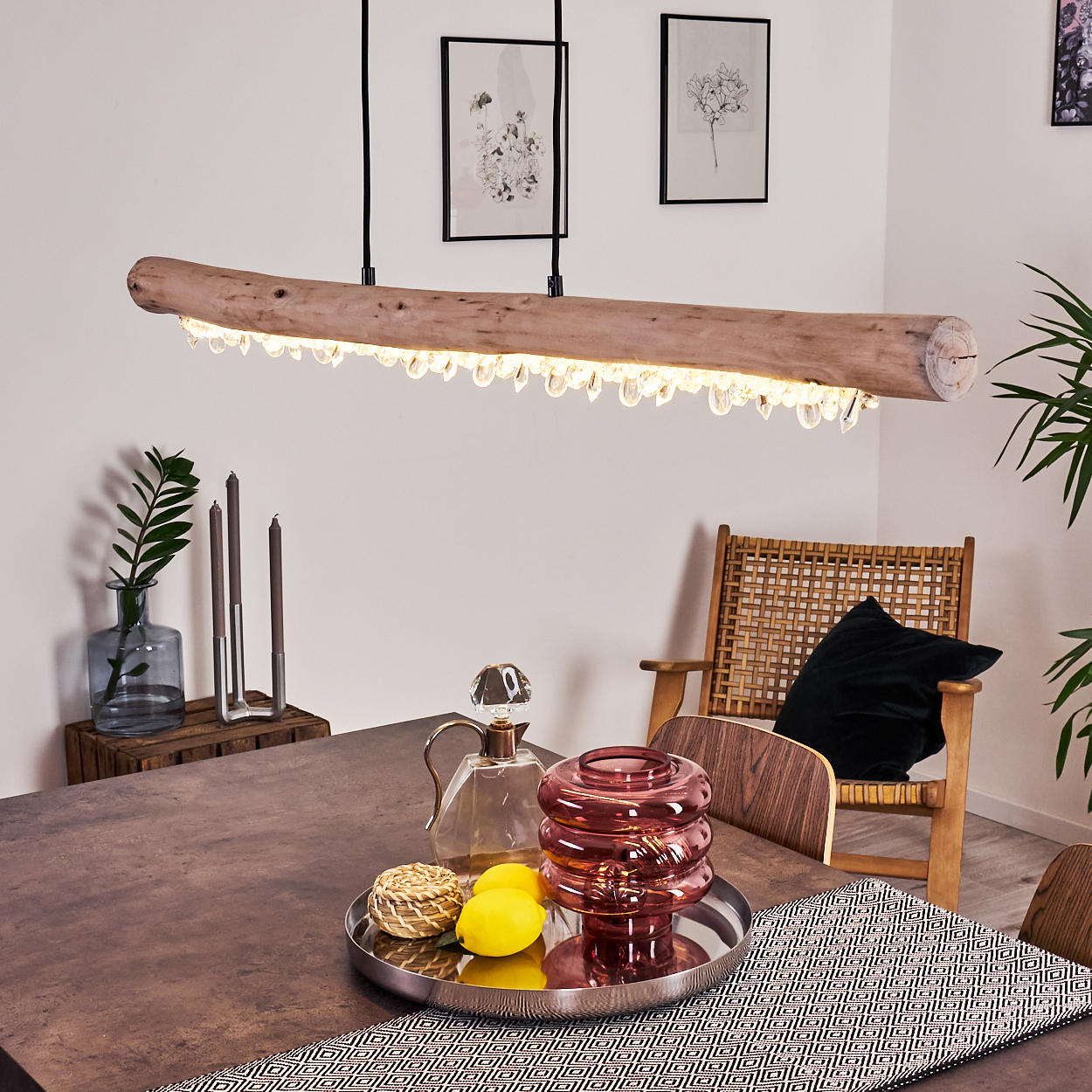 Ein Holzbalken-Kronleuchter mit Kristallanhängern hängt über einem Tisch mit Dekor.