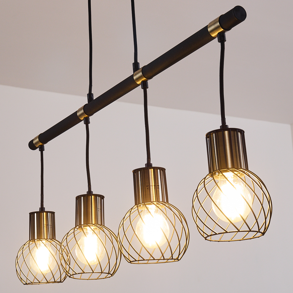 Moderne Pendelleuchte mit vier Lampenschirmen aus Metallkäfigen und schwarzem Balken.