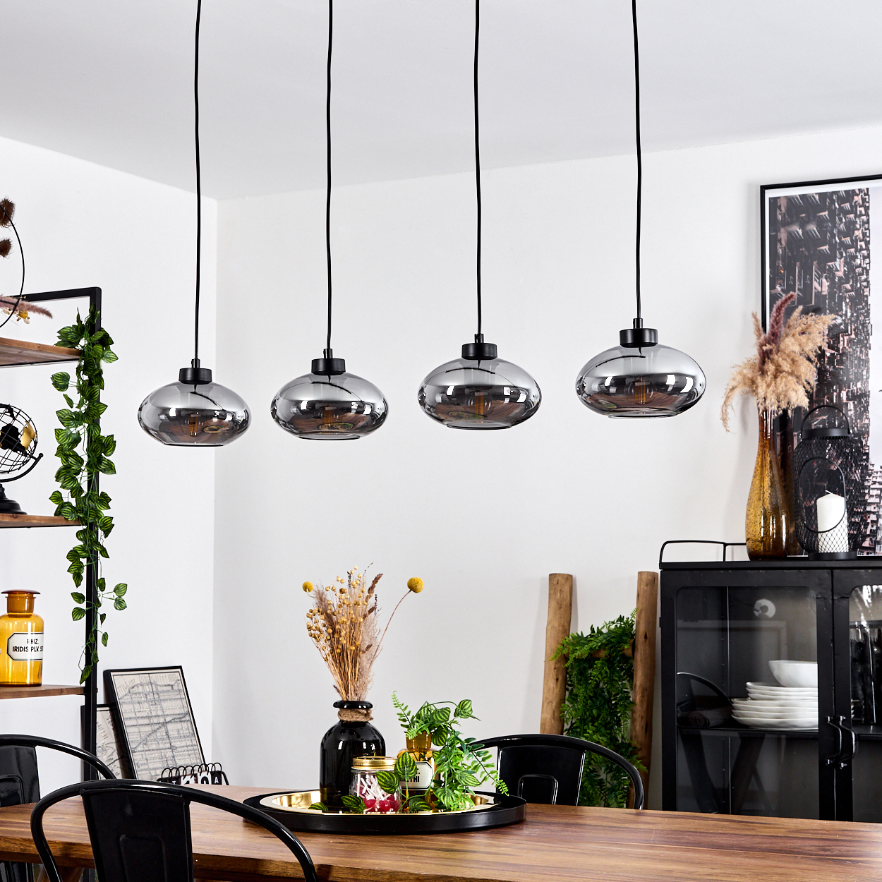 Vier hängende Lampen mit rauchglasnen Schirmen über einem Holztisch.