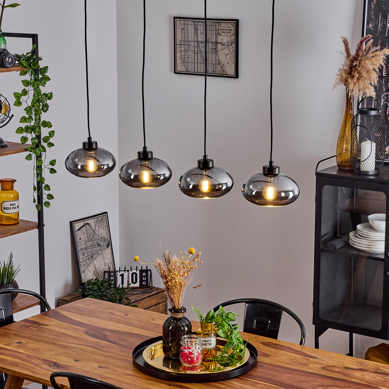 Esszimmer mit vier Hängelampen über Holztisch, dekoriert mit Vasen.