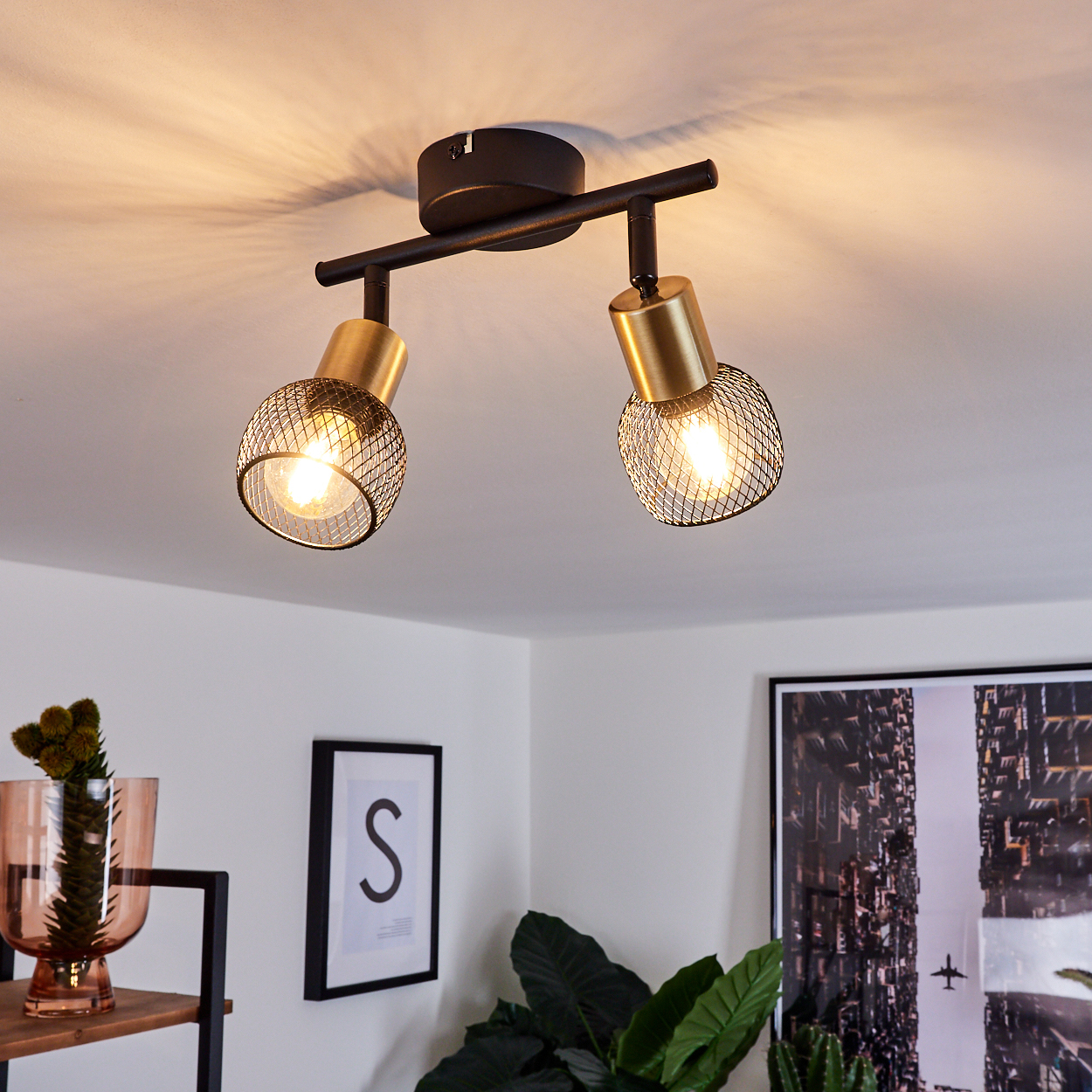 Zwei goldene und schwarze Deckenstrahler mit Gitterschirm leuchten an der Decke.
