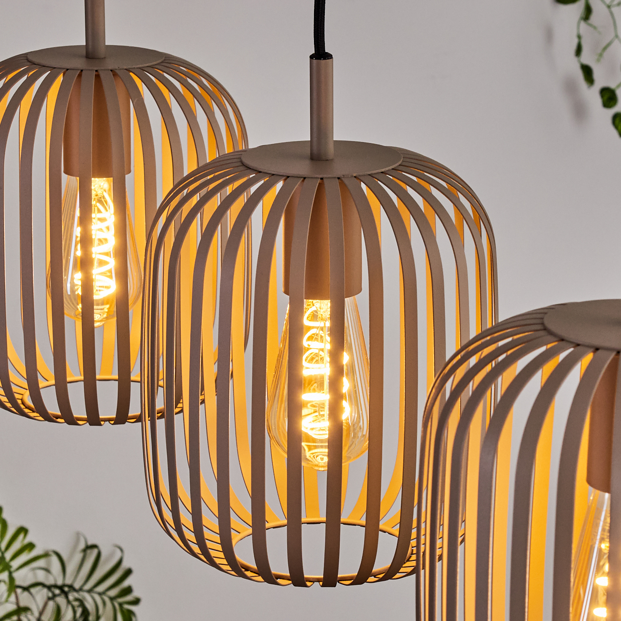Drei moderne Pendelleuchten mit Käfig-Schirmen und sichtbaren Glühbirnen.