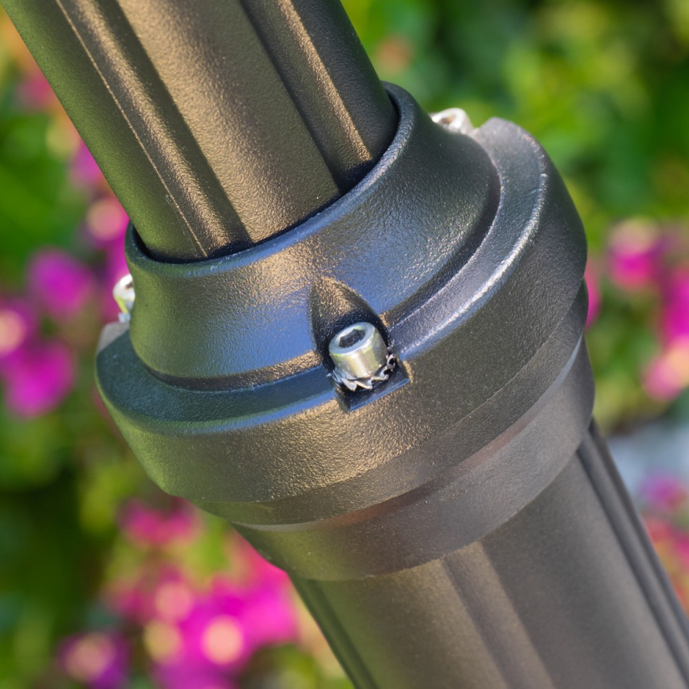 Schwarzer Mast mit Schraubdetails vor unscharfem rosa Blumenhintergrund.