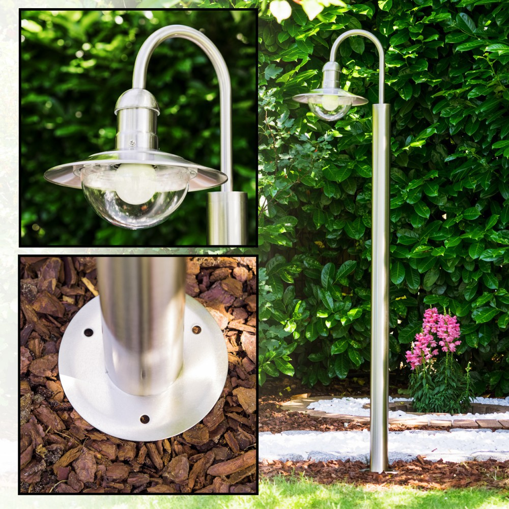 Edelstahl-Gartenlampe mit Glaskuppel vor üppigem Grün und Blumen.