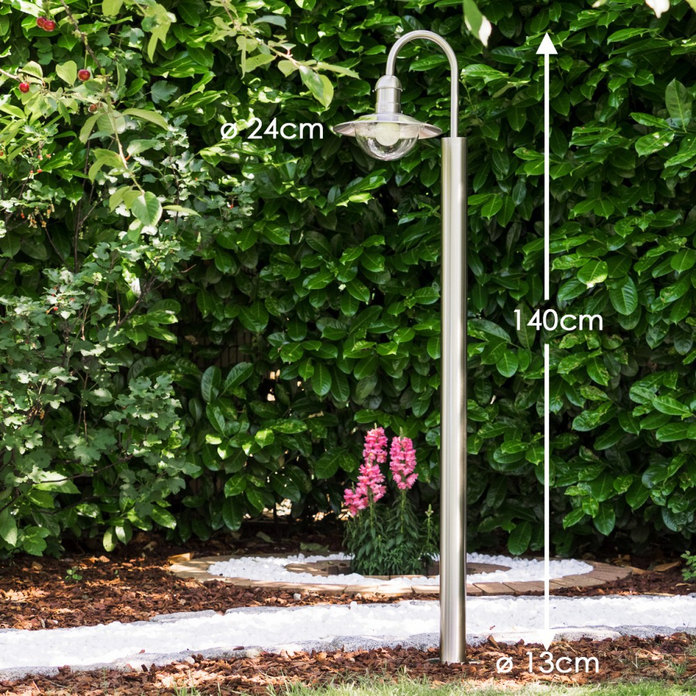 Ein polierter Metallpfosten mit Lampe steht vor einer Hecke. Maße: 140cm hoch, 24cm Lampendurchmesser.