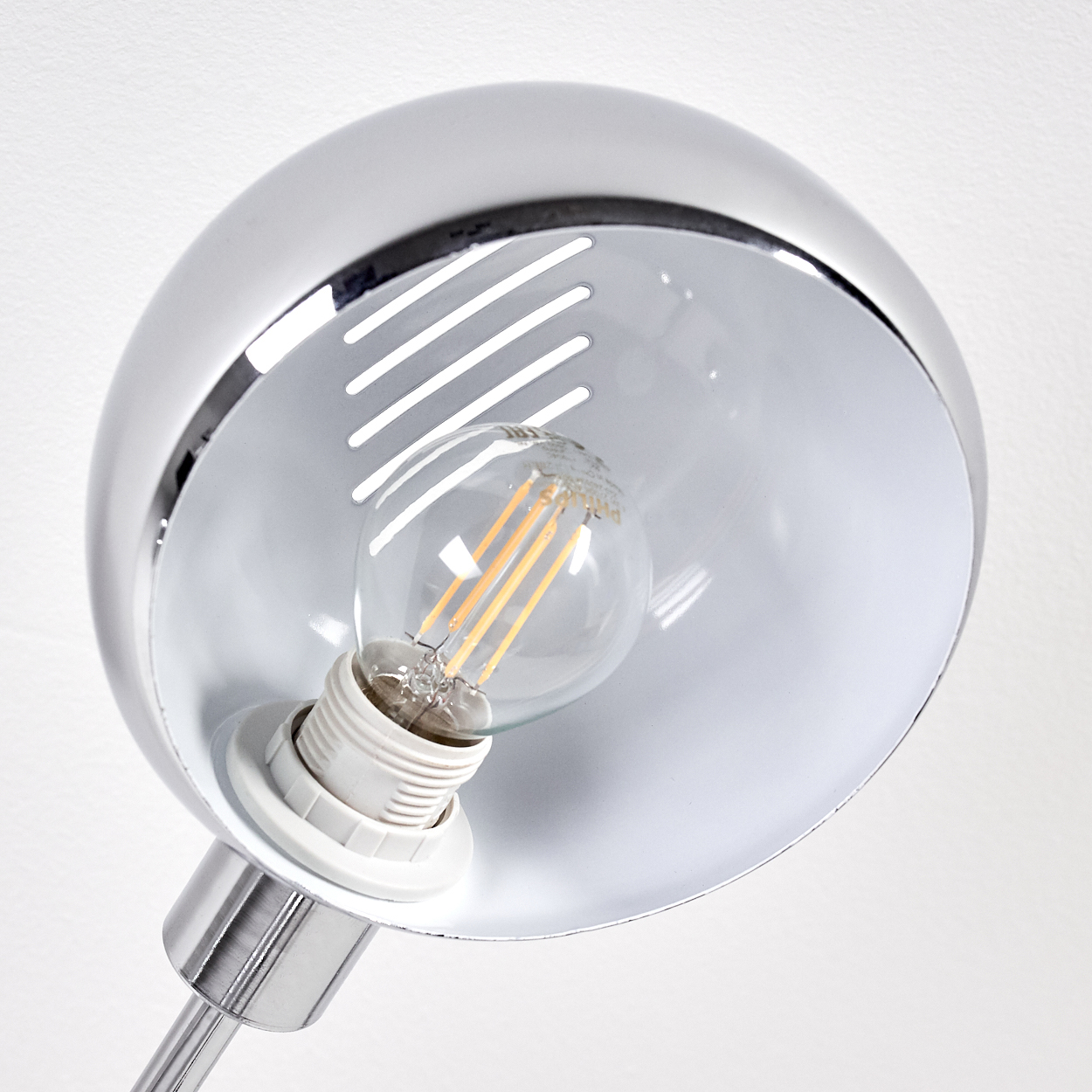 Eine Glühbirne in einer silbernen Lampe mit Lüftungsschlitzen.