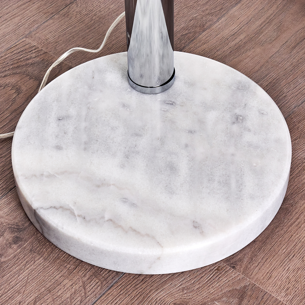 Runder Marmorsockel mit Metallstütze auf Holzboden.