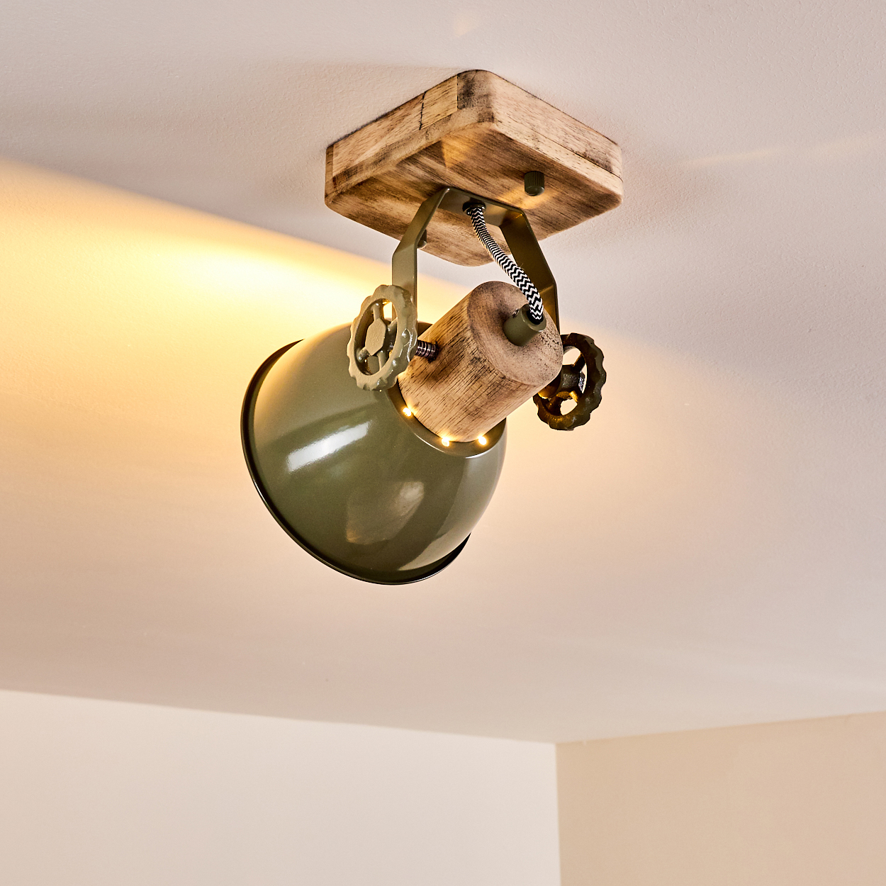 Grüne Lampe mit Holzdetail an Decke montiert, mit Zahnrädern.