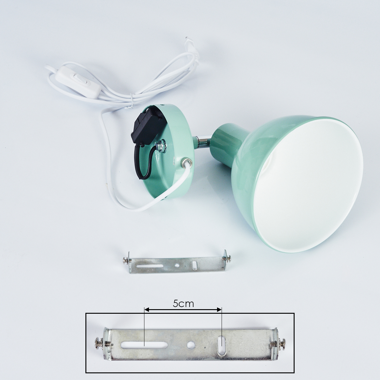 Eine grüne Lampe mit weißem Kabel und Schalter, daneben eine Halterung.