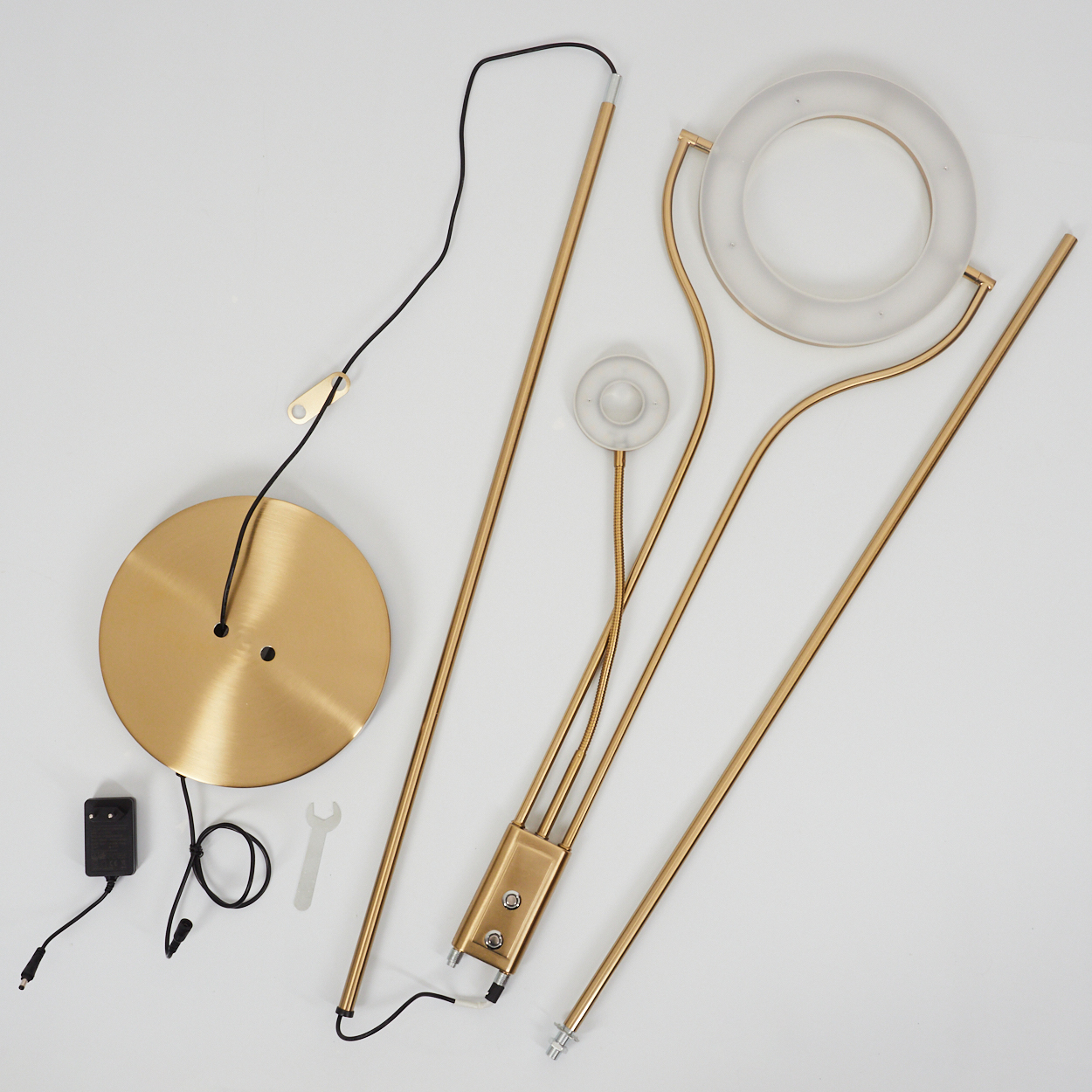 Teile einer goldenen Stehleuchte: Sockel, Stangen, Ring und kleiner Lampenschirm.