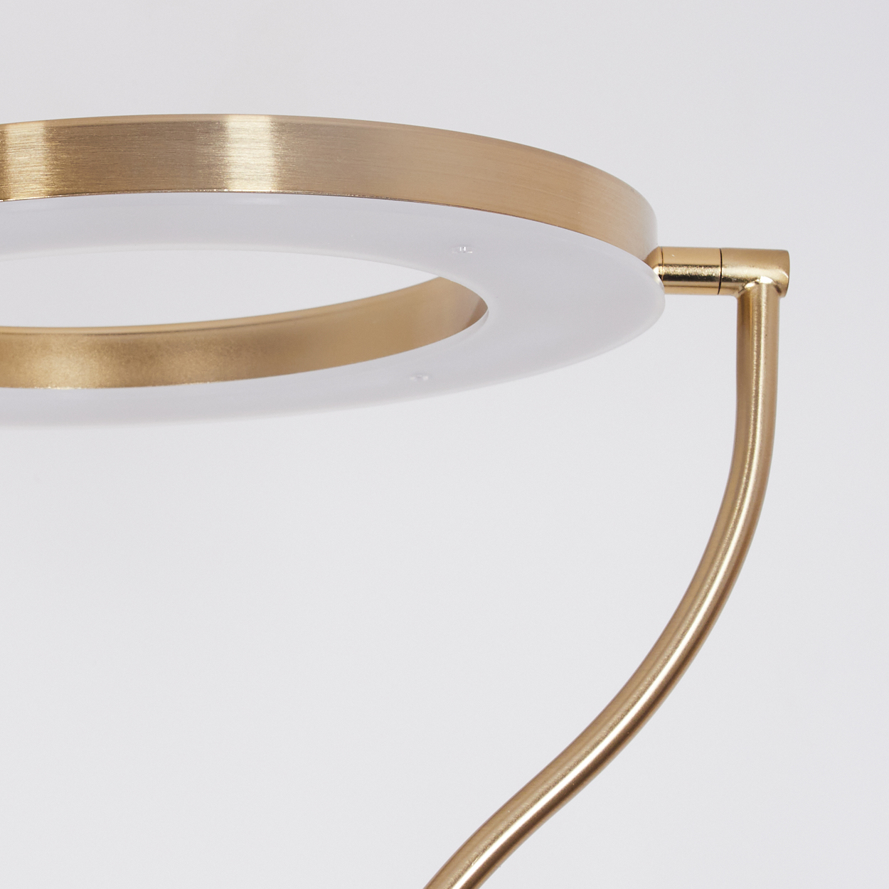 Goldener Ring mit weißer Mitte und gebogenem Ständer auf weißem Grund.