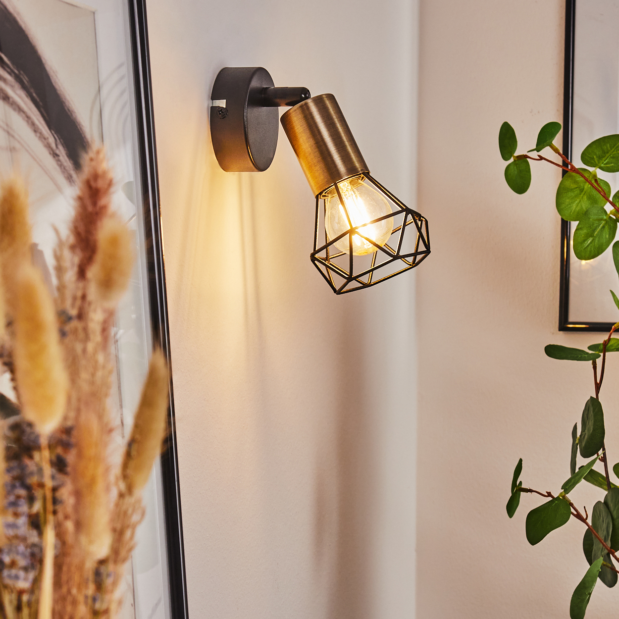 Ein moderner Wandspot mit Messingdetail und schwarzem Gitter beleuchtet die Wand.