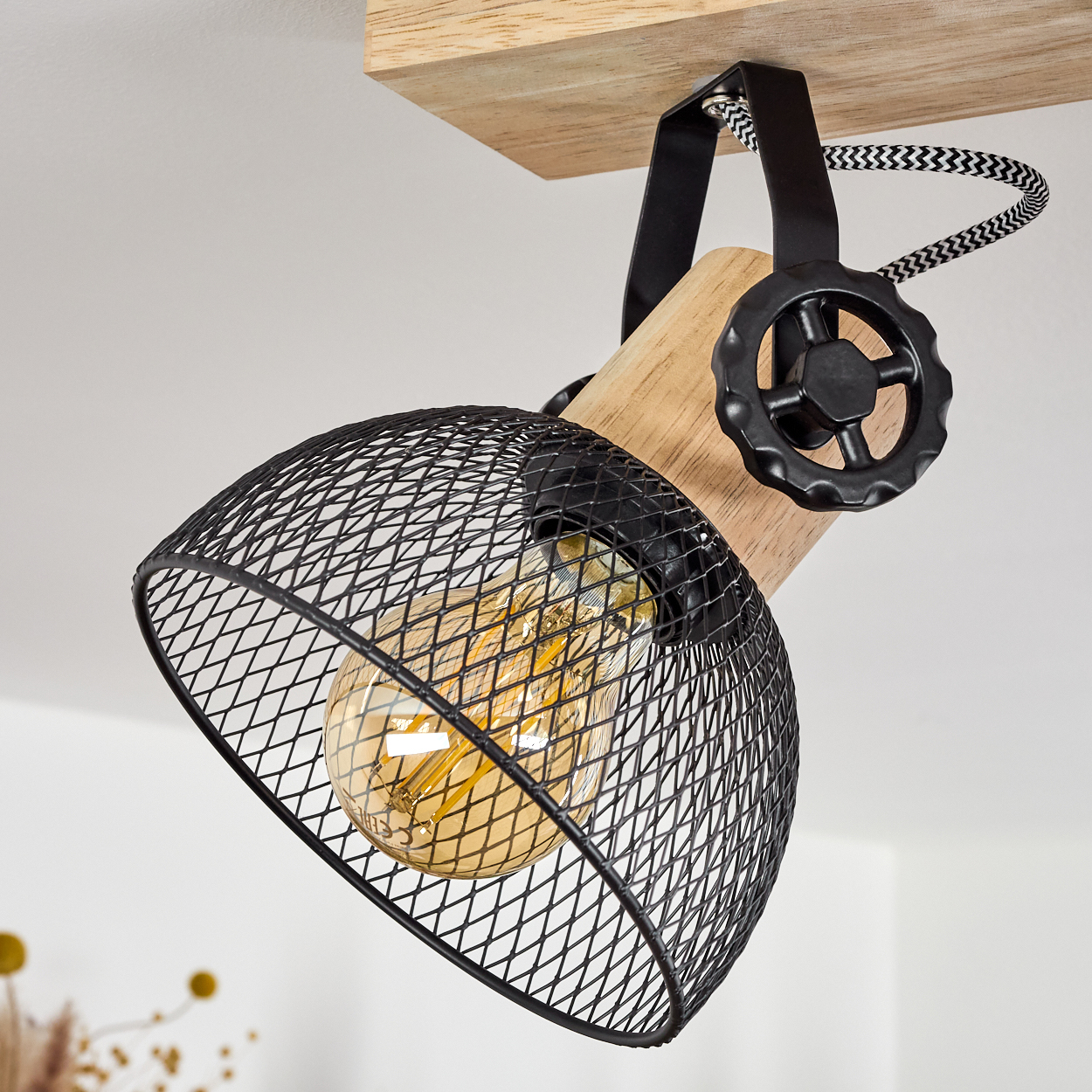 Industrielle Lampe mit Holz, schwarzem Gitter und Glühbirne.
