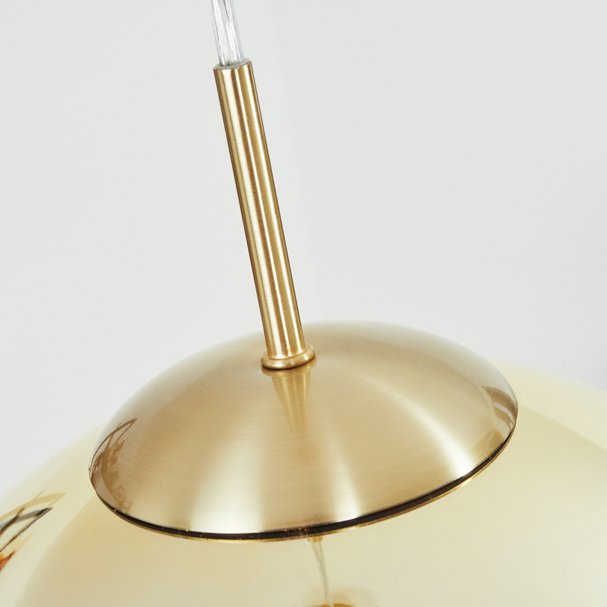 Messingfarbene Aufhängung einer Lampe mit cremefarbenem Lampenschirm.