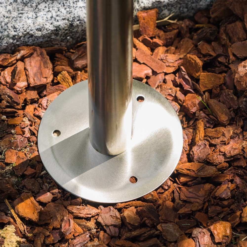 Metallpfosten mit runder Basis auf Rindenmulch, daneben Steine.