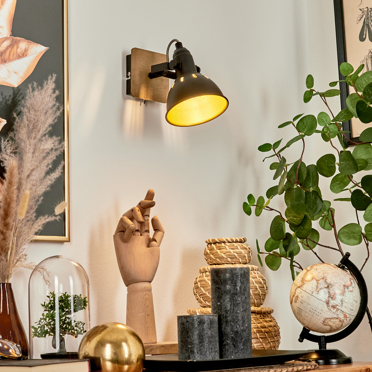 Eine Wandleuchte beleuchtet einen Schreibtisch mit Dekorationsgegenständen.