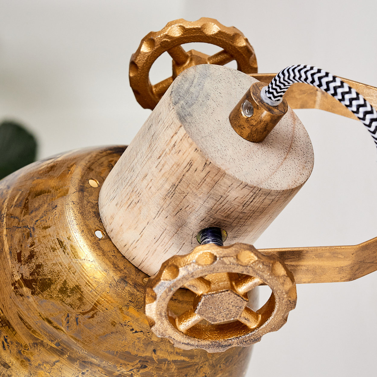 Detail eines Lampenkopfes aus Holz und Messing mit Zahnrädern und Kabel.