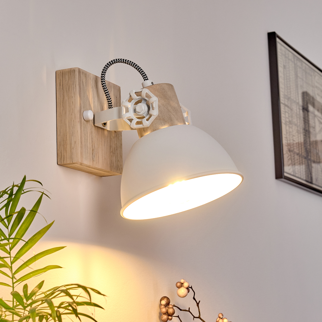 Eine weiße Wandleuchte mit Holzsockel und verstellbarem Schirm beleuchtet den Raum.