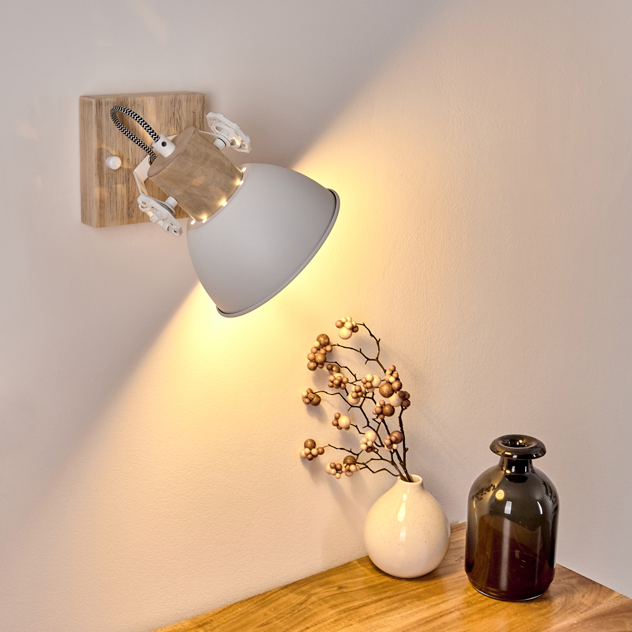 Ein Wandlicht aus Holz und Metall mit weißem Schirm beleuchtet eine Wand.