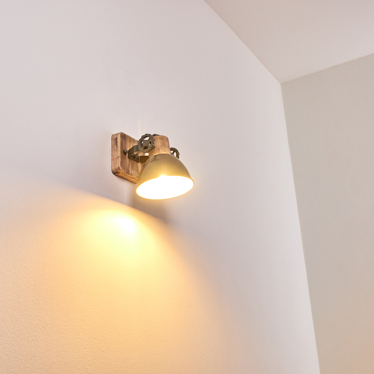 Eine Wandleuchte aus Holz und Metall mit einem Messingfarbenen Schirm leuchtet hell.