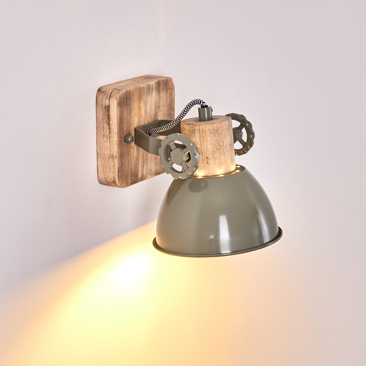 Wandleuchte mit Holzsockel, Metallschirm und Zierrädern. Beleuchtet die Wand.