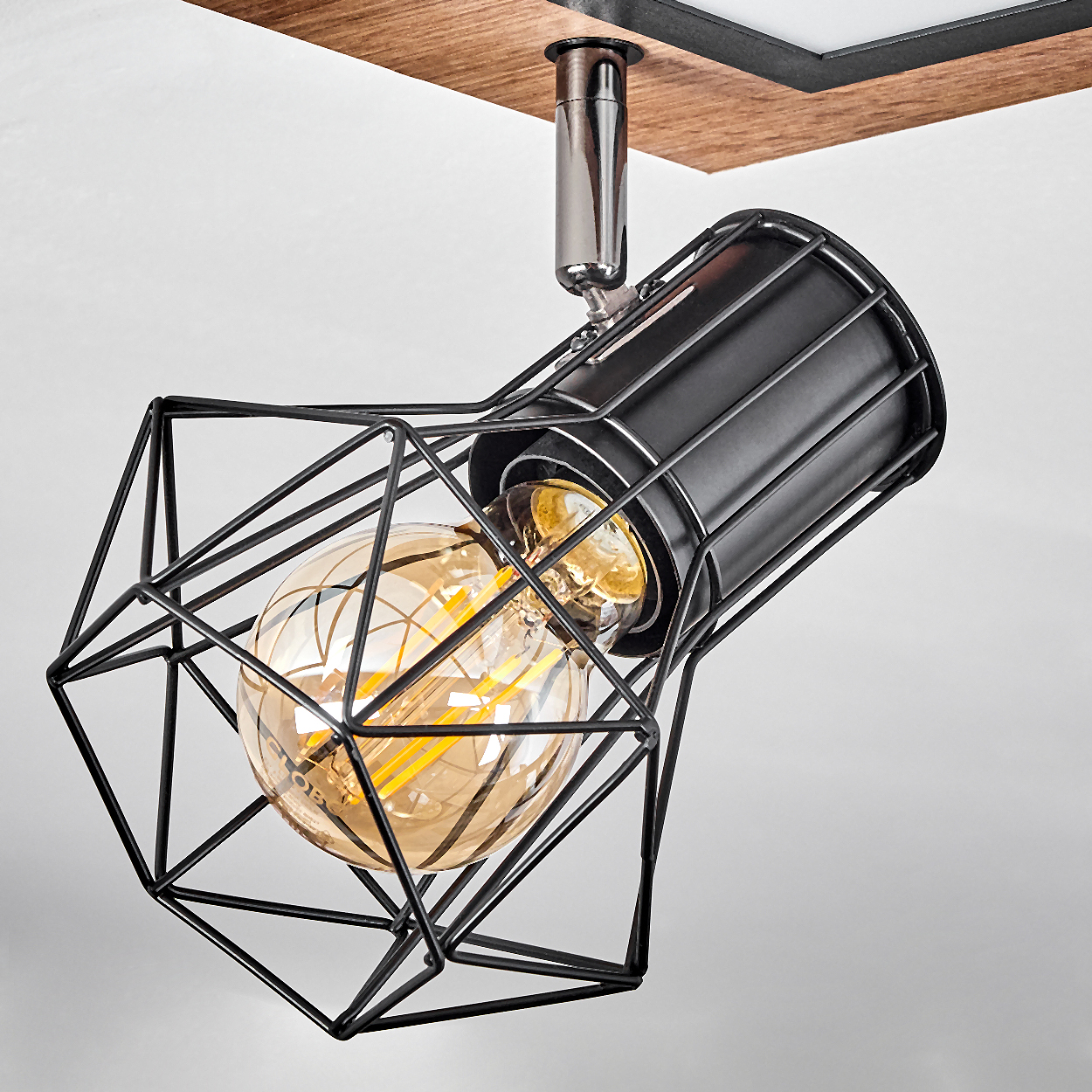 Eine schwarze Drahtkäfig-Lampe mit einer bernsteinfarbenen Glühbirne.